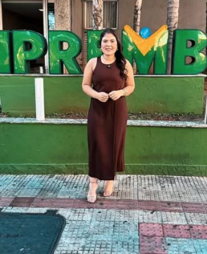 Mulher em pé diante do letreiro colorido com o nome IPREMB.