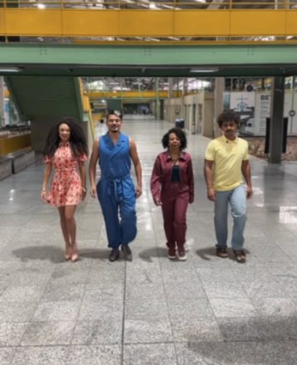 Quatro pessoas caminham lado a lado por um corredor coberto.